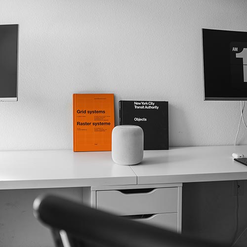 long desk with monitors and books on it